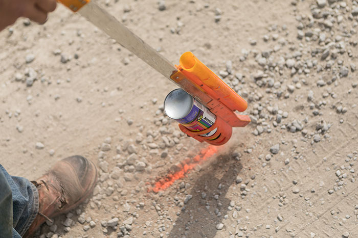 central cable worker marking cement with orange paint