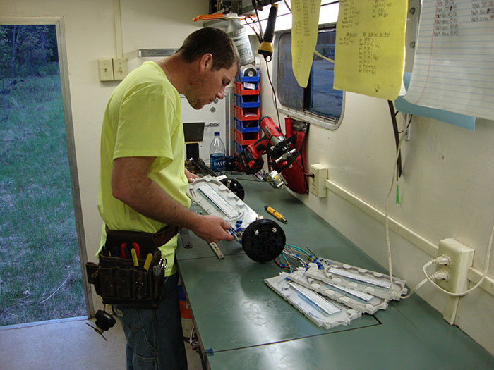 central cable worker looking at cable plates in a trailer