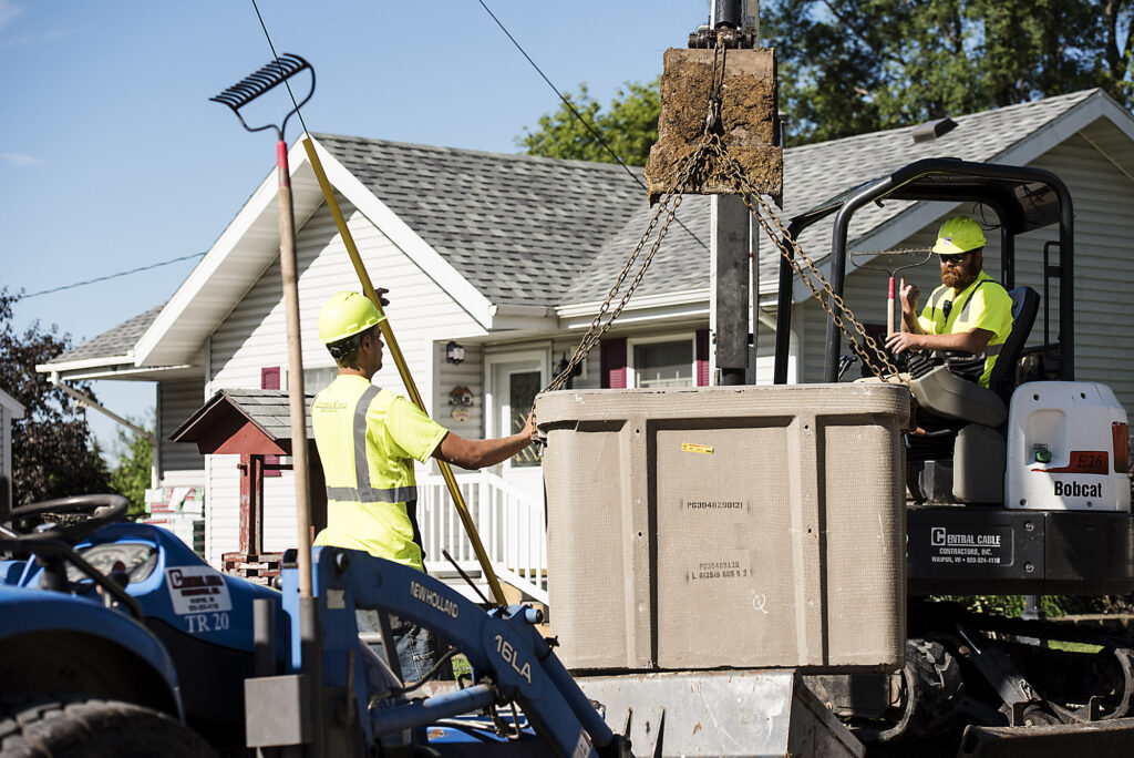 central cable workers using a crane to move a heavy unit