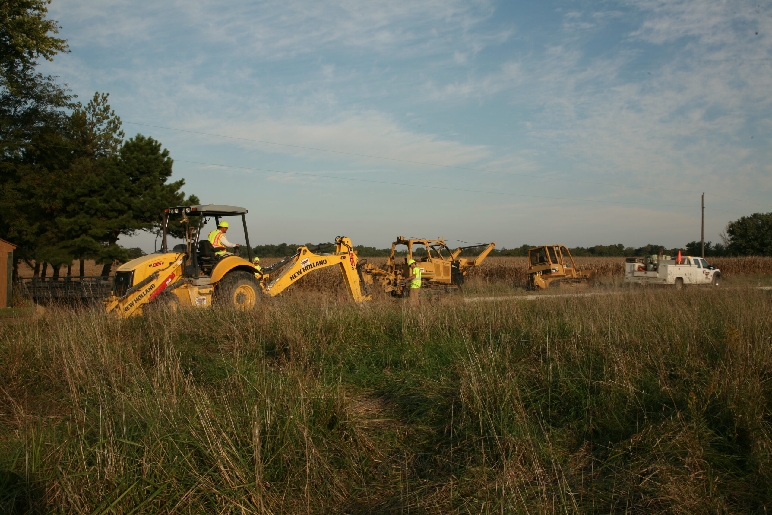 central cable workers in their new holland machines on the side of a road