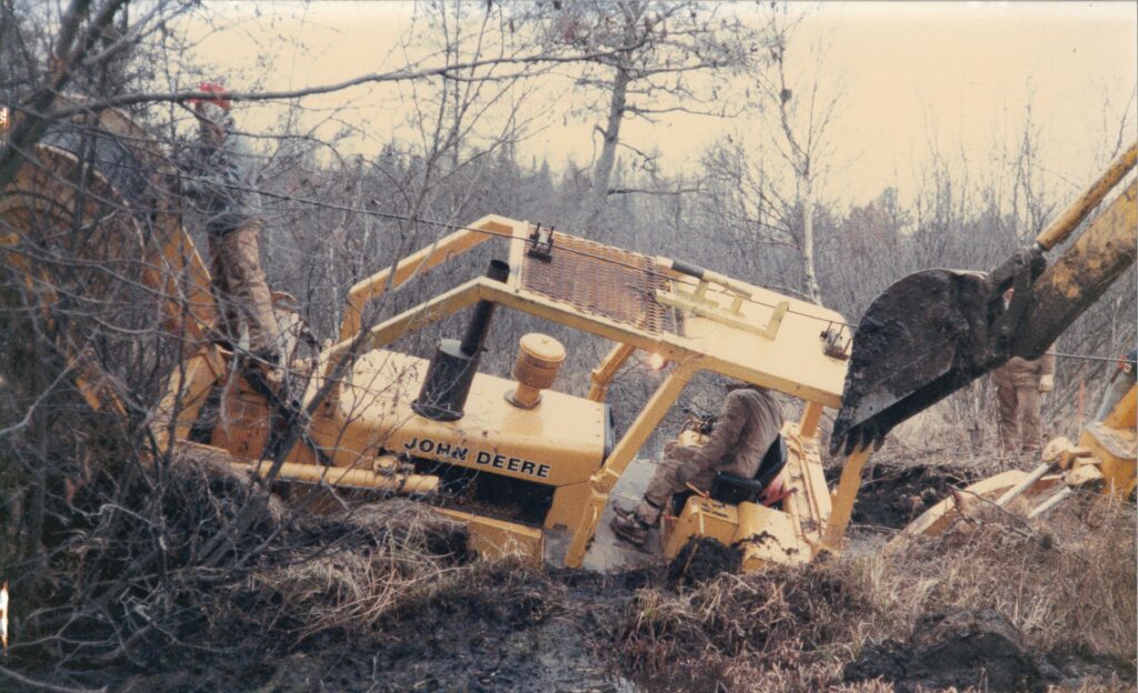 old photo of a central cable worker stuck in the water in his john deere machine